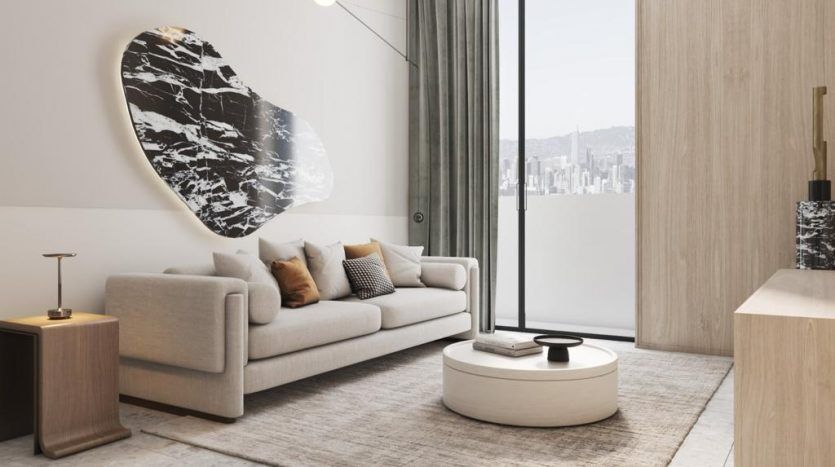 Salon moderne avec un canapé gris clair orné d'oreillers, une grande œuvre d'art ovale en noir et blanc au-dessus et une vue sur le paysage urbain à travers la baie vitrée présentant l'immobilier Dubaï