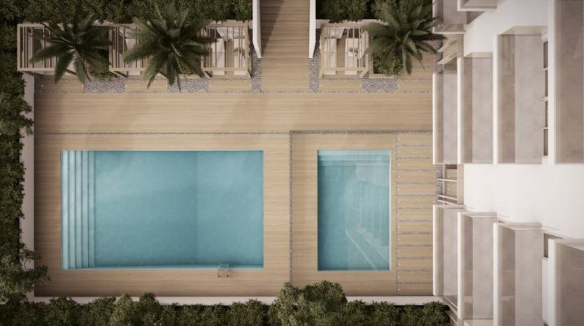 Vue aérienne d'un projet architectural moderne à Dubaï comprenant deux grandes piscines bordées de palmiers et flanquées de bâtiments, reliées par un chemin sablonneux.