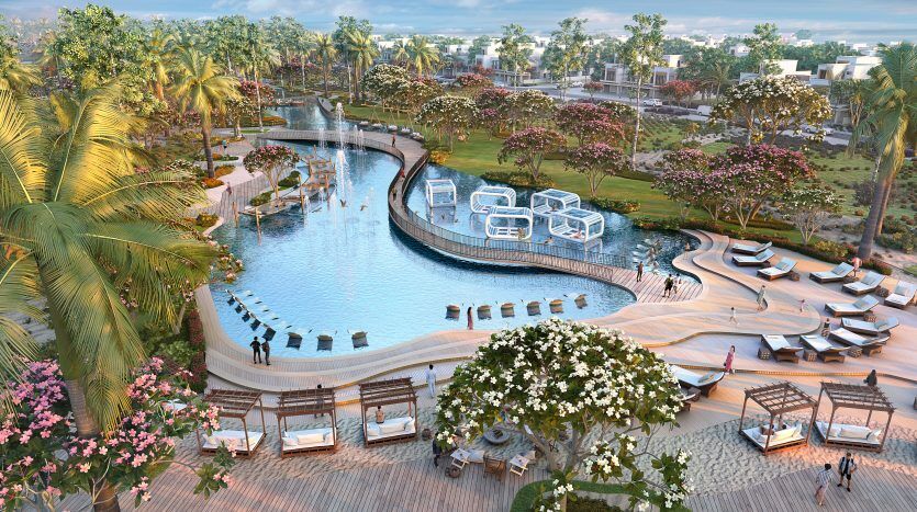 Un luxueux complexe tropical doté d'une vaste piscine, de coins salons et d'un aménagement paysager luxuriant, avec des structures modernes en forme de cube flottant sur l'eau à Dubaï.