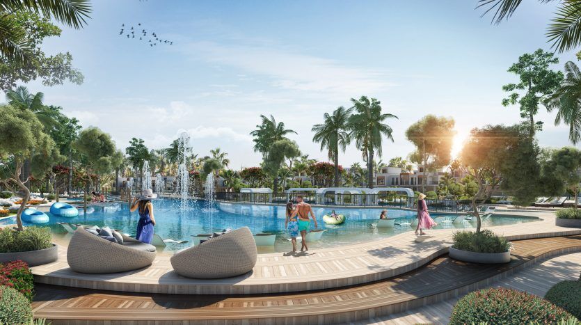 Une piscine animée avec des gens pratiquant des activités nautiques, entourée de palmiers luxuriants et d'espaces de détente modernes, gérée par une agence immobilière de premier plan à Dubaï, avec un coucher de soleil radieux en arrière-plan.