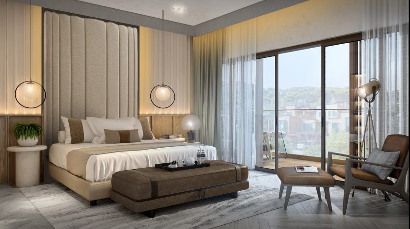Une chambre moderne et élégante dans un appartement de Dubaï comprenant un grand lit avec une literie moelleuse, une chaise dans le coin, des luminaires ronds suspendus, des baies vitrées avec des rideaux transparents et