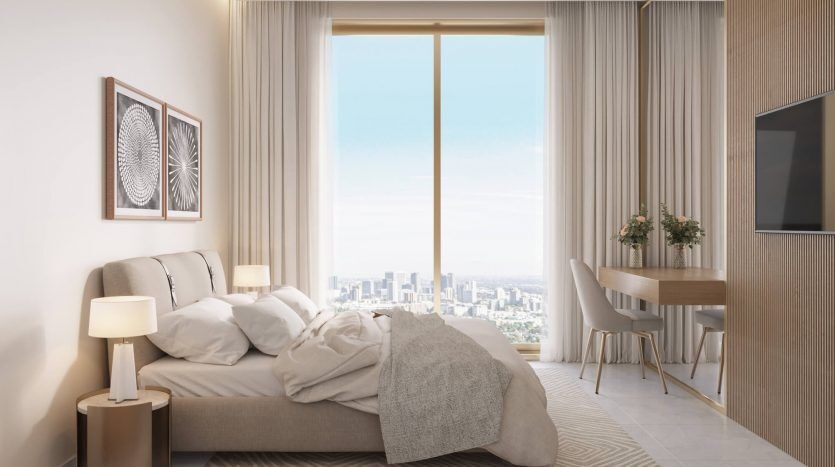 Une chambre moderne dans un appartement de Dubaï avec une grande fenêtre offrant une vue sur la ville. La chambre dispose d'un lit soigneusement fait, d'un petit coin repas et d'une télévision fixée au mur. Doux, naturel