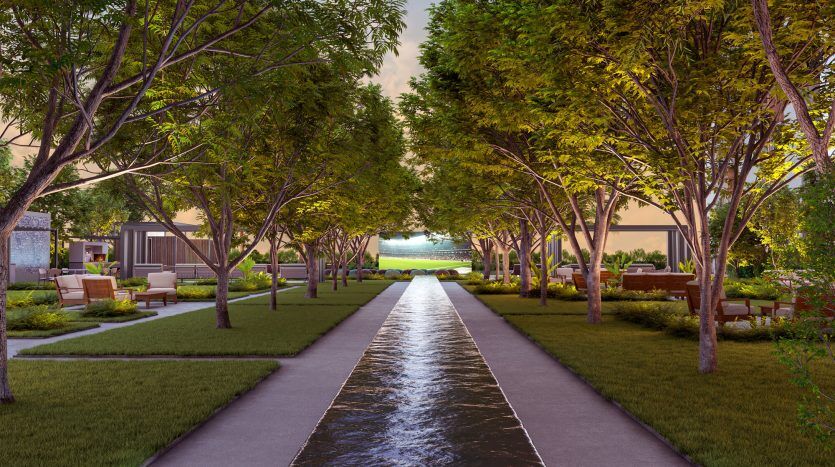 Un paysage serein présentant un design symétrique avec un canal d'eau central flanqué de sentiers, de pelouses luxuriantes et de rangées d'arbres illuminés menant à une villa lointaine à Dubaï au crépuscule.