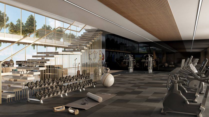 Un intérieur de salle de sport moderne dans une villa de Dubaï avec une large gamme d'équipements d'entraînement, notamment des tapis roulants, des supports de musculation et un tapis de yoga, avec des murs en verre et de la lumière naturelle.