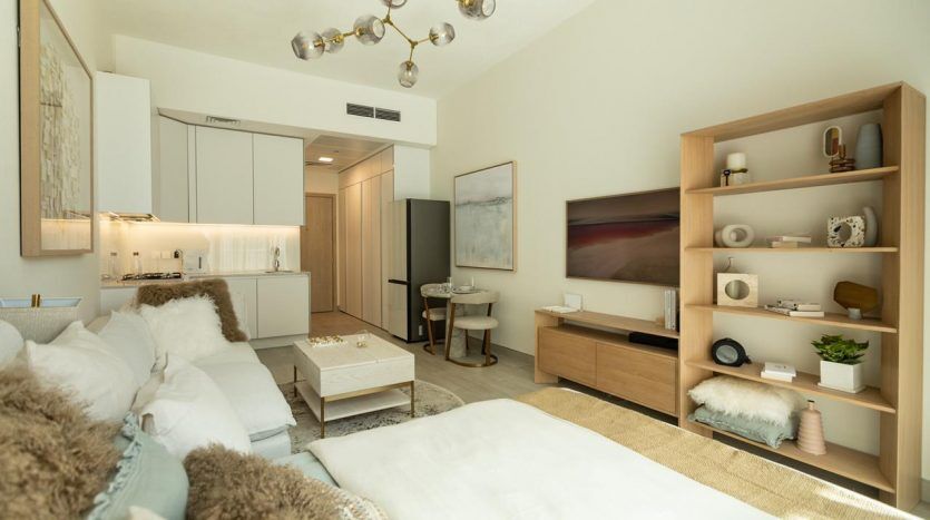 Studio moderne à Dubaï comprenant un espace de vie décloisonné soigneusement organisé avec une kitchenette, un coin repas et une chambre, le tout sous un lustre sphérique unique. Palette de couleurs claires et décoration contemporaine.