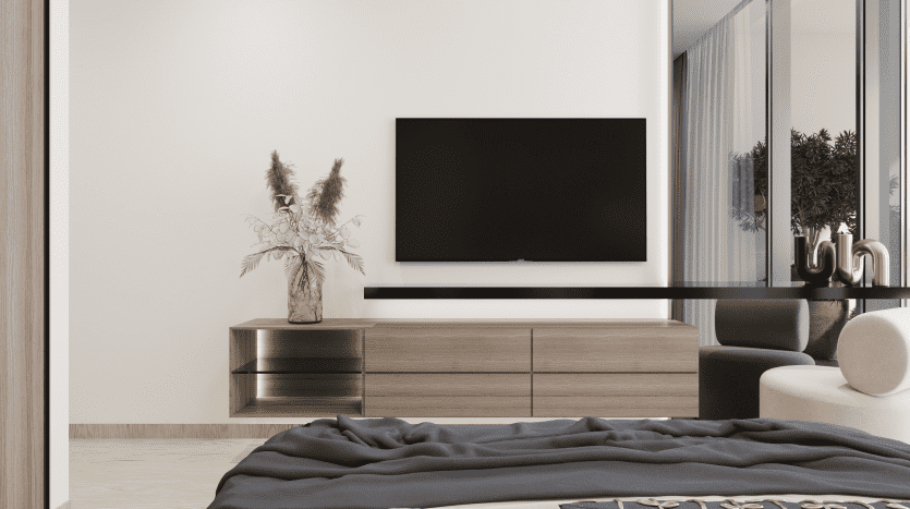 Chambre minimaliste moderne avec une grande télévision à écran plat montée sur un mur blanc au-dessus d'une commode en bois, à côté d'un vase avec de l'herbe de pampa dans une villa de Dubaï. Un lit moelleux est au premier plan