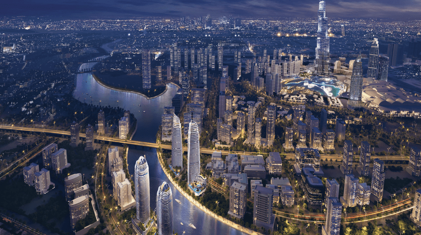 Vue aérienne nocturne d'un paysage urbain animé de Dubaï avec des gratte-ciel illuminés, des rivières sinueuses et des routes animées, dominées par une haute tour sur la droite.
