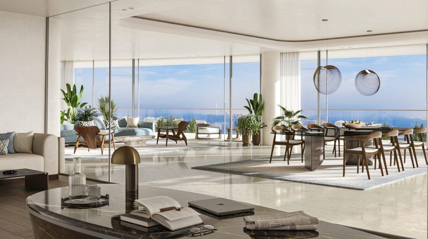 Salon et salle à manger luxueux et modernes dans une villa de Dubaï offrant une vue imprenable sur l'océan à travers des baies vitrées, élégamment meublés avec un mélange de chaises contemporaines et de plantes tropicales.
