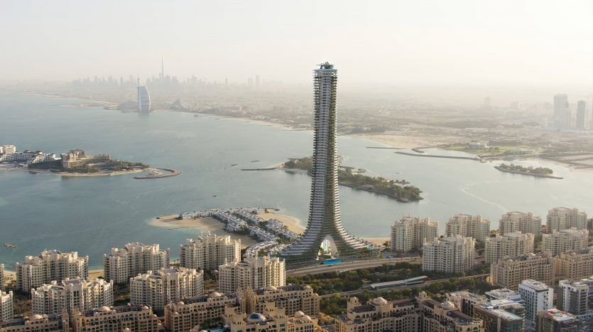 Vue aérienne d'un gratte-ciel en spirale unique surplombant un littoral de Dubaï, entouré de petits bâtiments résidentiels et d'îles sablonneuses, avec un paysage urbain en arrière-plan brumeux.