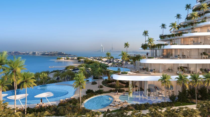 Luxueuse villa côtière à Dubaï, dotée de terrasses à plusieurs niveaux, chacune avec piscines et palmiers, surplombant une baie sereine avec un voilier au loin.