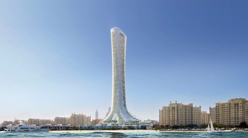 Un gratte-ciel futuriste et sinueux s'élève bien en évidence au-dessus de l'horizon côtier de Dubaï, flanqué d'autres bâtiments et de bateaux naviguant sur des eaux bleu vif sous un ciel clair.