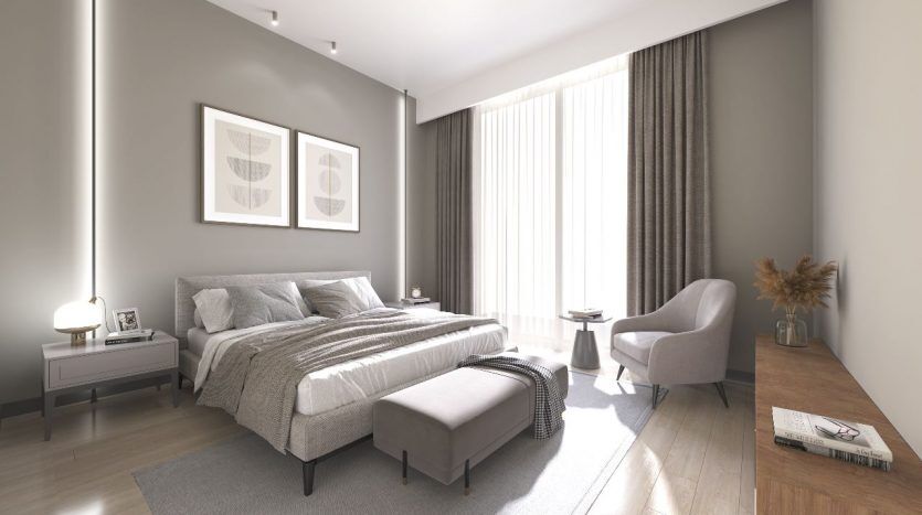 Une chambre moderne dans un appartement de Dubaï comprenant un grand lit avec une literie grise, deux œuvres d'art encadrées symétriquement au-dessus, des rideaux blancs, un parquet, un fauteuil près de la fenêtre et un petit