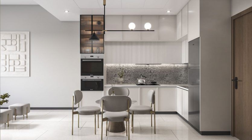 Une cuisine moderne aux tons neutres avec des appareils électroménagers intégrés, un coin repas avec quatre chaises, des suspensions et des œuvres d'art murales décoratives proposées par une agence immobilière de Dubaï.