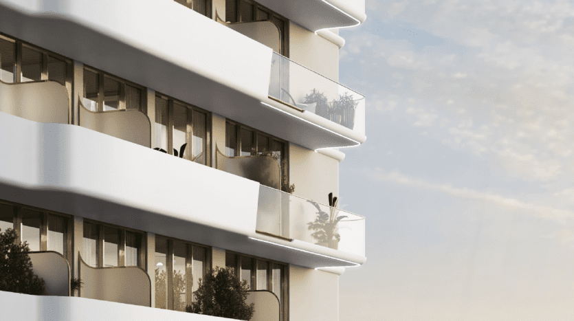 Immeuble d'appartements moderne à Dubaï avec balcons blancs incurvés ornés de plantes, sous un ciel clair au coucher du soleil.