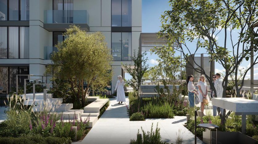 People socializing in a modern rooftop garden in a Dubai apartment with lush greenery, seating areas and contemporary architecture.