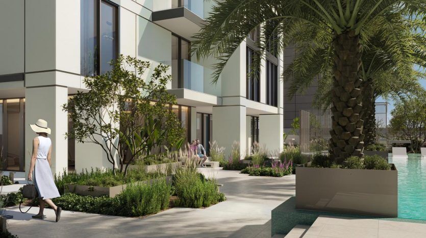 A modern residential villa in Dubai with large glass windows and white walls, surrounded by lush greenery. People relax by a turquoise pool lined with tall palm trees and well-manicured bushes. A woman in