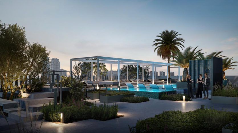 A modern rooftop terrace at dusk with a luxurious pool, elegant outdoor furniture, lush greenery and a small group of people enjoying the space under a blue pergola in an elite villa in Dubai.