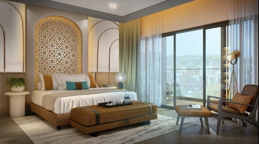 Lujoso dormitorio en una villa de Dubai con cama king-size, cabecero ornamentado, ventanales con vistas y una elegante decoración acentuada por un sillón esquinero de estilo vintage y una moderna iluminación.