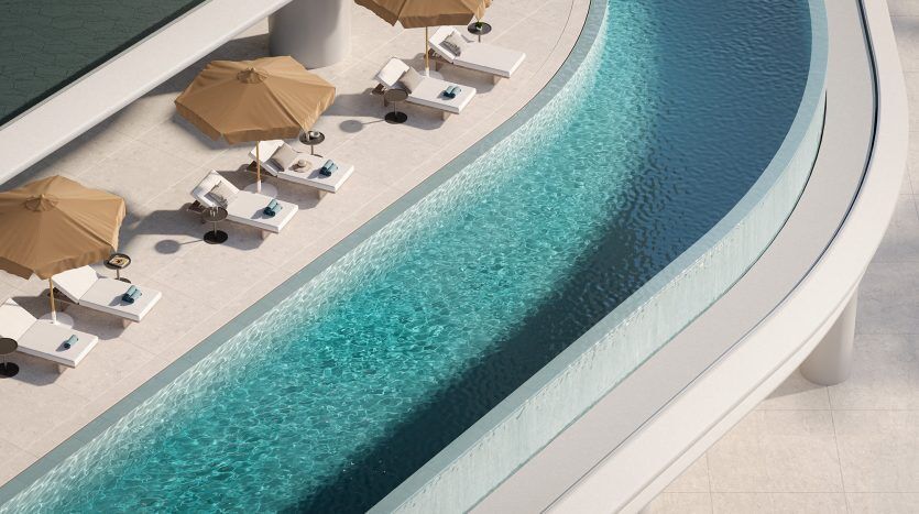 Vue aérienne d'une piscine extérieure incurvée aux eaux bleues cristallines, entourée de parasols beiges et de chaises longues blanches dans une villa de luxe à Dubaï par une journée ensoleillée.