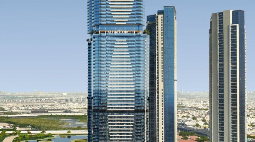 Vue aérienne d'un grand gratte-ciel moderne avec une façade en verre bleu et des bandes horizontales distinctives, situé à côté d'une autoroute très fréquentée et entouré d'autres immeubles de grande hauteur à Dubaï.
