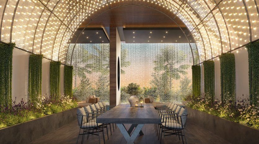 Une élégante salle à manger extérieure sous un treillis incurvé orné de lumières scintillantes, flanquée de jardins verticaux et donnant sur un décor serein et boisé - un cadre idéal pour ceux qui s'intéressent à l'immobilier.