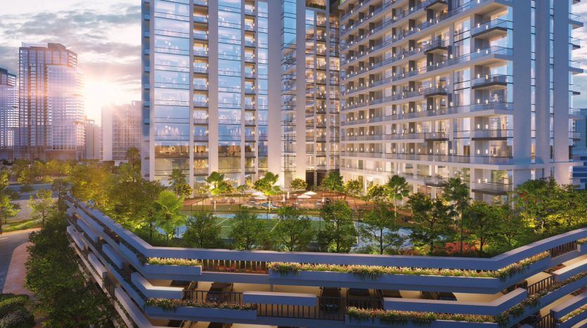 Appartements résidentiels modernes de grande hauteur à Dubaï avec balcons et verdure luxuriante au coucher du soleil, avec une structure de parking complexe à plusieurs niveaux en dessous. La chaude lumière du soleil met en valeur les détails architecturaux.