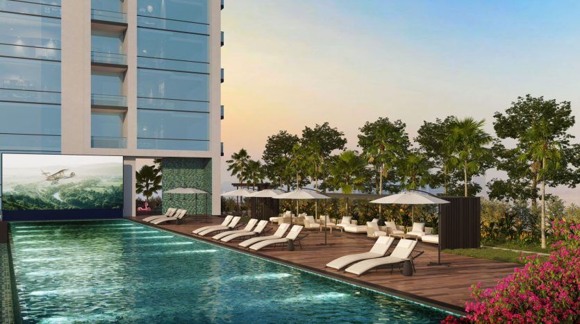 Rendu 3D d'une luxueuse piscine à Dubaï au coucher du soleil avec des chaises longues et des parasols, flanquée d'un immeuble moderne de grande hauteur d'un côté et d'une verdure luxuriante de l'autre.