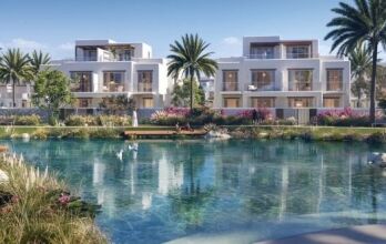 Villas résidentielles de luxe à Dubaï surplombant un lac artificiel tranquille aux eaux bleu clair. Des jardins luxuriants et des palmiers entourent la zone, renforçant la sérénité du cadre. Les cygnes nagent paisiblement