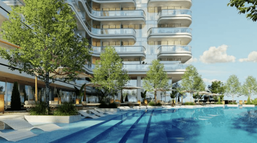 Des arbres luxuriants et des transats entourent une luxueuse piscine extérieure dans un complexe d'appartements moderne à plusieurs niveaux à Dubaï, par une journée ensoleillée.