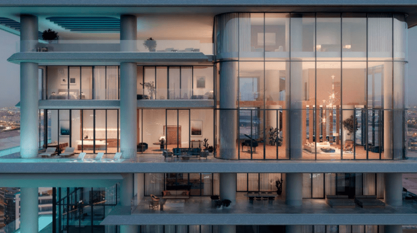 Vue extérieure d'un bâtiment moderne à plusieurs niveaux au crépuscule à Dubaï, présentant de grandes fenêtres en verre et des terrasses avec un paysage urbain en arrière-plan.