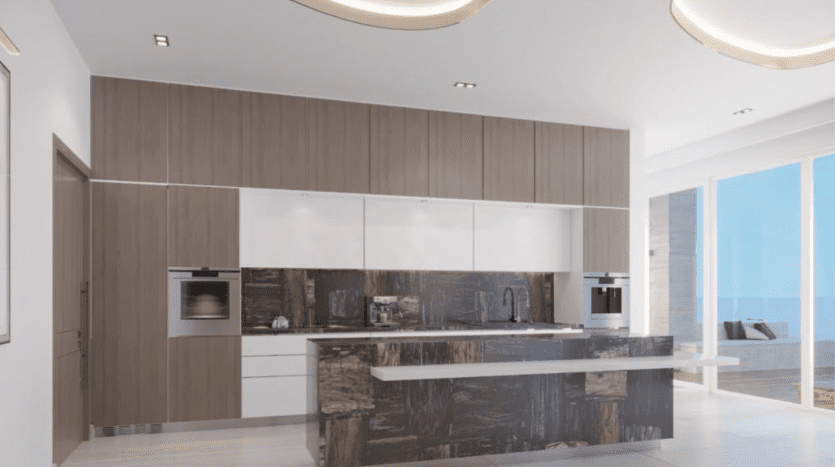Une cuisine moderne avec des armoires en bois élégantes, des comptoirs blancs, des appareils électroménagers intégrés et un grand îlot de cuisine. Il y a une vue sur l'océan à travers de grandes fenêtres en arrière-plan de cet appartement Dubaï