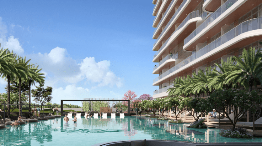 Une scène luxueuse au bord de la piscine avec des gens se relaxant dans et autour d'une grande piscine extérieure claire, entourée de palmiers et située en face d'un appartement moderne de grande hauteur à Dubaï avec des balcons incurvés.