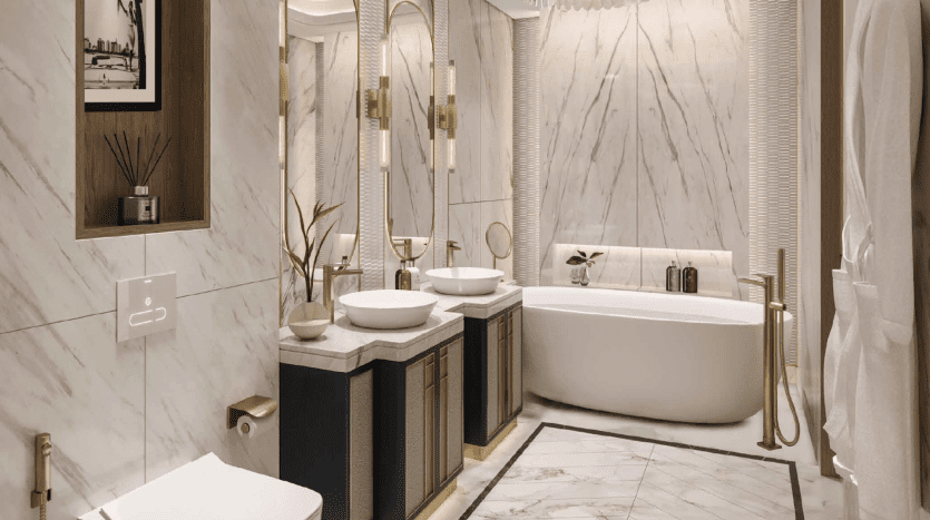 Une salle de bains luxueuse dans un appartement de Dubaï, avec des murs en marbre blanc, une baignoire autoportante, deux lavabos avec des miroirs ronds au-dessus, des luminaires dorés et des plantes vertes, créant un espace serein et élégant