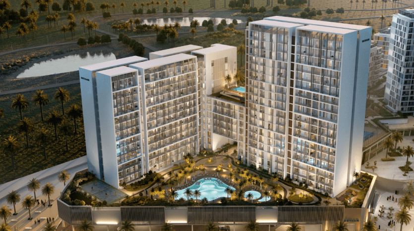 Vue aérienne d'un complexe d'appartements moderne de grande hauteur à Dubaï au crépuscule, avec des fenêtres éclairées, une piscine centrale, entourée de palmiers et d'autres bâtiments.