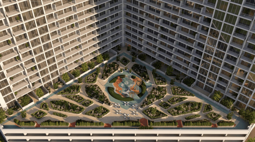 Vue aérienne d'une cour entourée d'immeubles d'habitation de grande hauteur à Dubaï, comprenant un jardin paysager avec des allées, des bancs et une fontaine centrale.