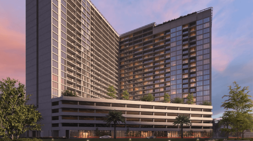Immeubles jumeaux modernes de grande hauteur dotés de vastes façades vitrées et d'un parking attenant à plusieurs niveaux, le tout sur fond de ciel vibrant au coucher du soleil. Verdure luxuriante et vue au niveau de la rue visible à Dubaï.