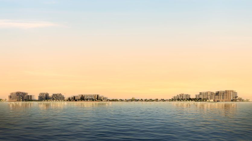 Vue de bâtiments modernes et de villas luxueuses à Dubaï sur un front de mer au coucher du soleil, avec des reflets scintillants sur la mer calme sous un ciel doux dégradé du bleu au jaune.