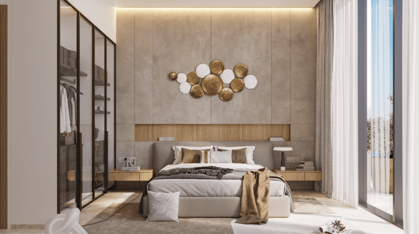 Une chambre moderne dans un appartement de Dubaï comprenant un grand lit avec des draps beiges, des décorations murales dorées élégantes, un éclairage d'ambiance et un parquet élégant. Une élégante armoire et un coin salon luxueux sont également visibles