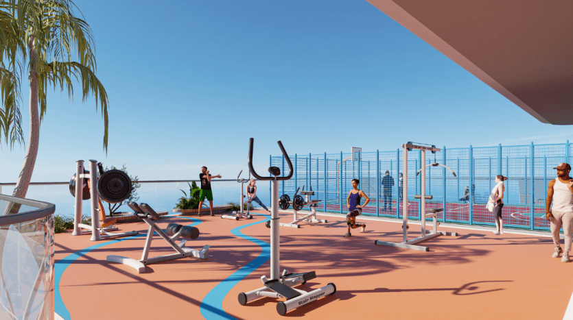 Salle de sport en plein air par temps clair avec plusieurs personnes s'exerçant à l'aide de divers équipements, notamment des poids et des bancs, à proximité d'un appartement de Dubaï avec une vue panoramique sur l'océan en arrière-plan.