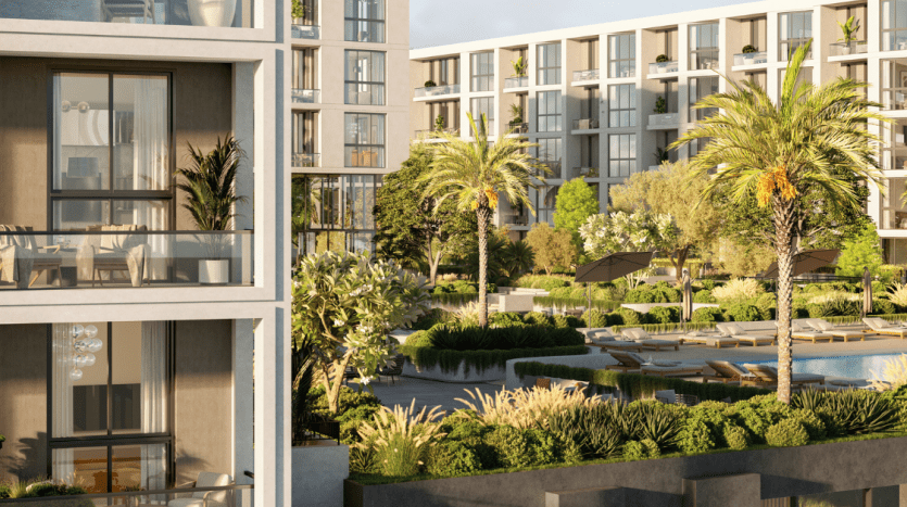 Un immeuble résidentiel de luxe avec des balcons spacieux donnant sur un jardin luxuriant avec des palmiers et une piscine dans un cadre urbain serein à l'heure d'or, parfait pour investir à Dubaï.