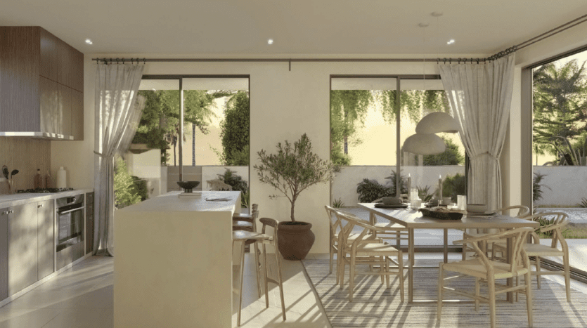 Cuisine ouverte moderne et coin repas avec lumière naturelle, meubles en bois, tons neutres et grandes fenêtres donnant sur un jardin, parfaits pour l'immobilier Dubaï.