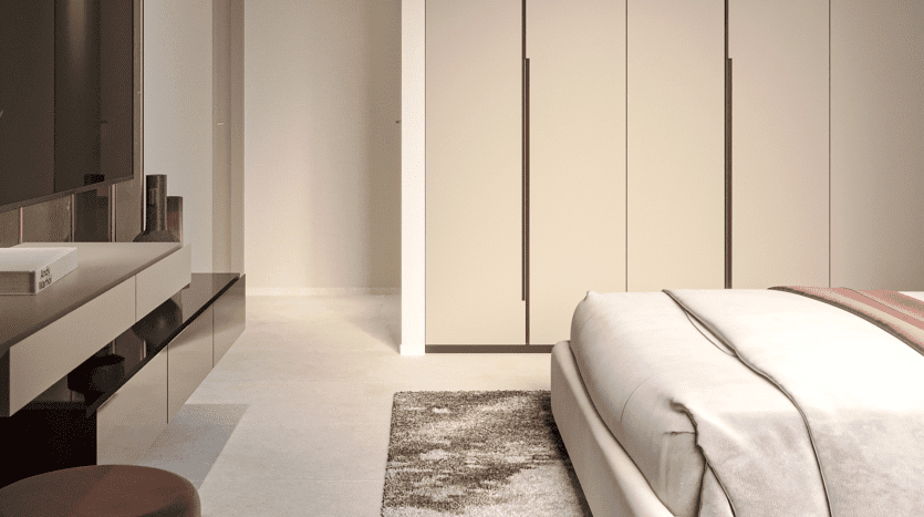 Une chambre moderne comprenant un grand lit avec une literie blanche et beige, une table d'appoint élégante avec un vase noir, des armoires beiges lisses et un tapis marron moelleux sur un sol en marbre clair dans un