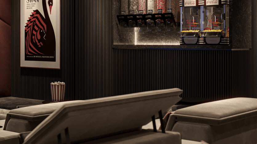 Un hall de cinéma faiblement éclairé dans une luxueuse villa de Dubaï avec des canapés gris moelleux, une machine à pop-corn et une affiche de film vintage au mur.