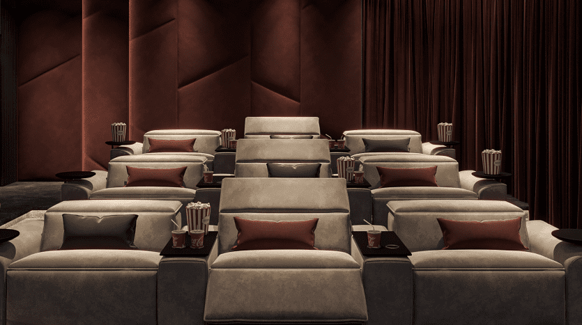 Luxueuse salle de cinéma privée dans un prestigieux appartement de Dubaï, dotée de fauteuils gris moelleux, chacun équipé d'une table d'appoint contenant du pop-corn et des boissons, sur fond de rideaux rouge foncé et