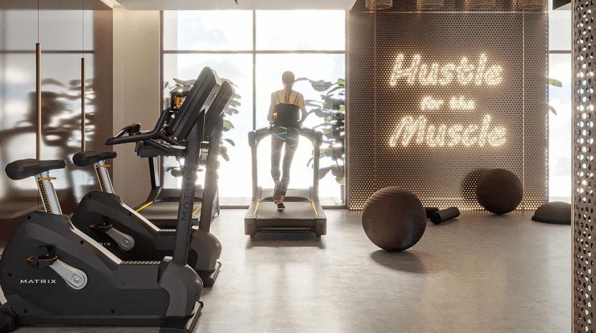 Une femme court sur un tapis roulant dans une salle de sport moderne d’une villa haut de gamme à Dubaï, avec la lumière du soleil pénétrant à travers de grandes fenêtres. Le mur devant indique « Hustle for that muscle » en lettres lumineuses.
