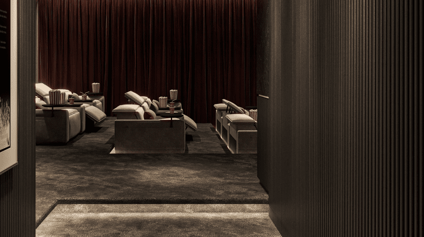 Un home cinéma luxueux et faiblement éclairé avec des rideaux rouge foncé et des fauteuils inclinables confortables installés en rangées sur une moquette sombre dans une villa privée à Dubaï. L'espace dégage une atmosphère chaleureuse