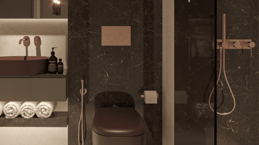 Une salle de bains moderne et luxueuse dans un appartement à Dubaï, dotée d'un robinet, d'un lavabo et d'accessoires de douche en or rose, accentués par des murs en marbre foncé et une pile de serviettes blanches soigneusement pliées.