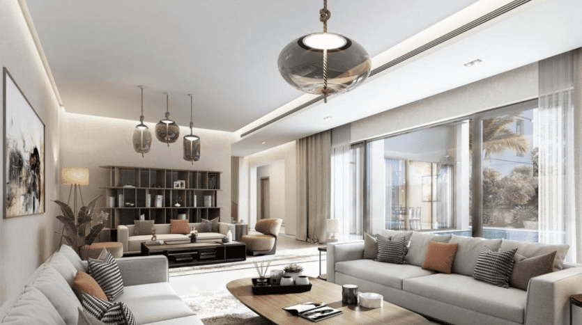 Salon moderne dans une propriété de l'immobilier Dubaï avec des tons neutres, un canapé sectionnel, une table basse en verre, des suspensions et de grandes fenêtres donnant sur un patio.