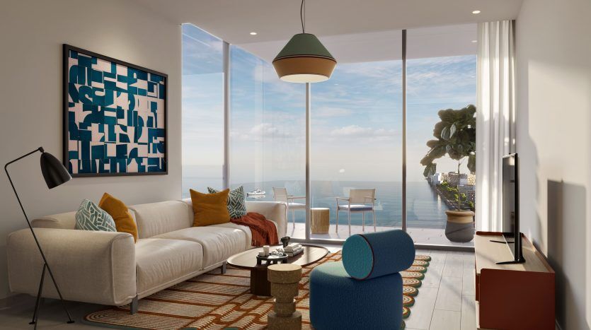 Salon moderne dans une villa de Dubaï avec un canapé blanc, un fauteuil bleu et des coussins colorés. Elle dispose d'une grande fenêtre avec vue sur la mer, d'œuvres d'art aux murs et d'une décoration intérieure élégante.