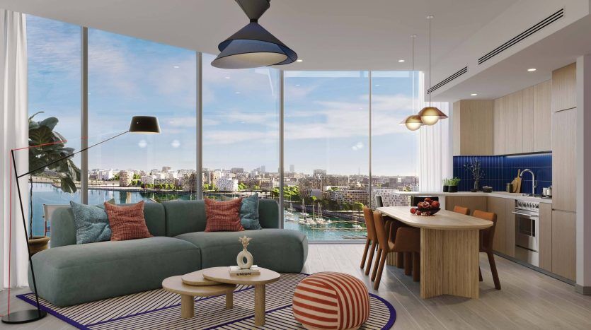Salon moderne dans une villa de Dubaï avec un canapé bleu sarcelle, une table ronde en bois et des oreillers colorés. De grandes fenêtres offrent une vue sur la ville. Il y a une cuisine bleue en arrière-plan et un tapis coloré